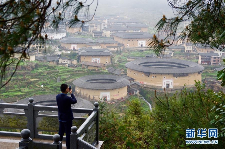 3月16日，一名游人在福建初溪土楼群观景台上拍照。